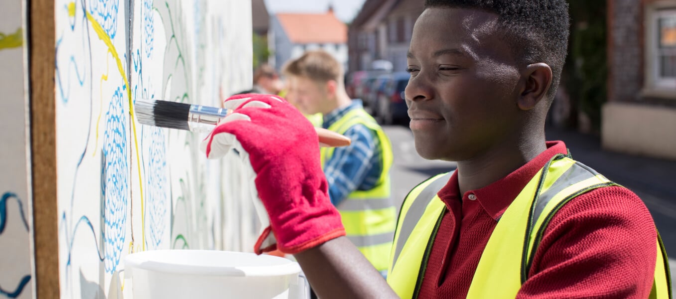 A worker with a high visibility vest on painting a wall