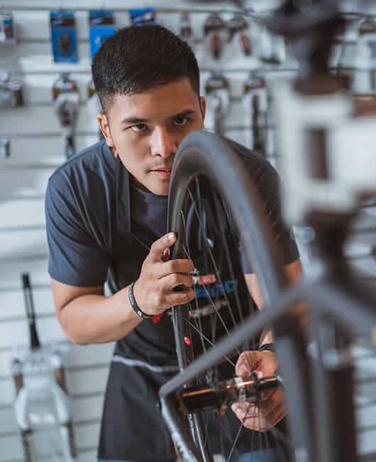 Employers-home-wwfe-1 A young bicycle mechanic apprentice fixing a wheel