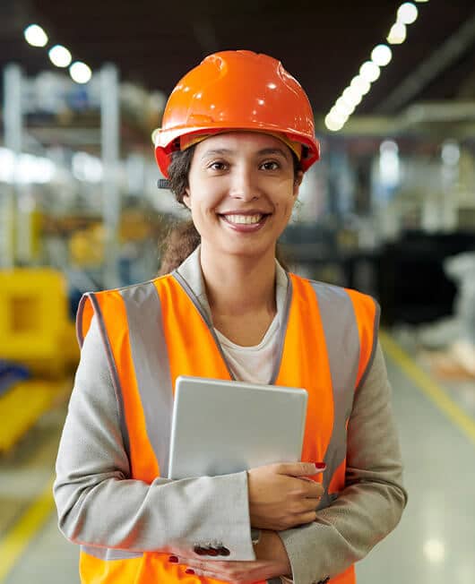 Participants-home-wwfe-1 A female engineering worker in an orange hard hat and high visibility vest in a factory