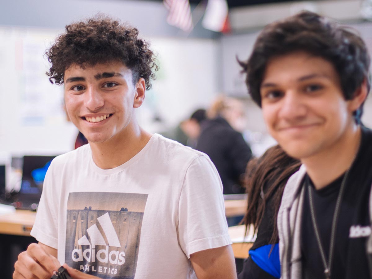Two teenage boys smiling in class