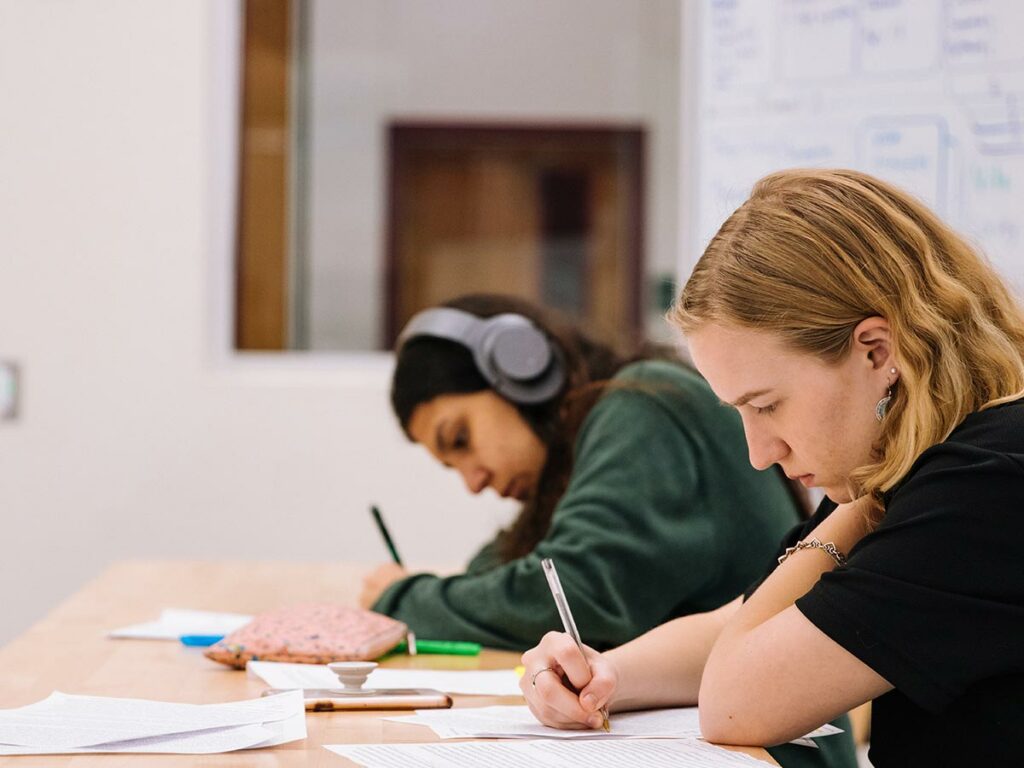 Two teenage girls writing in class