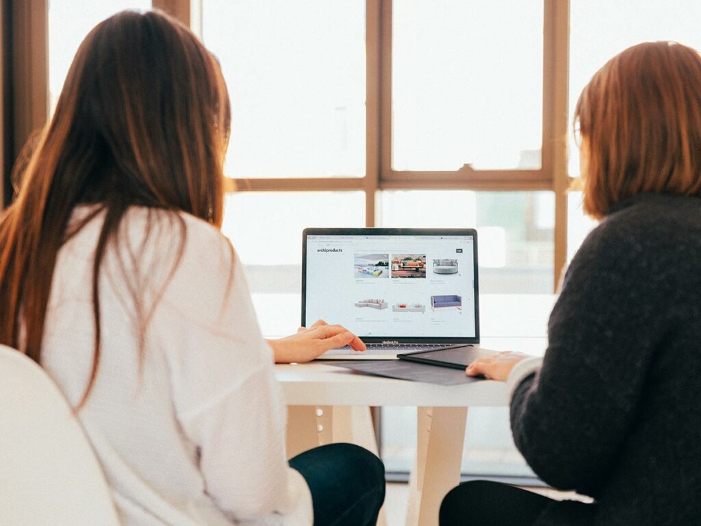 Two females looking at a laptop screen in a bright office space