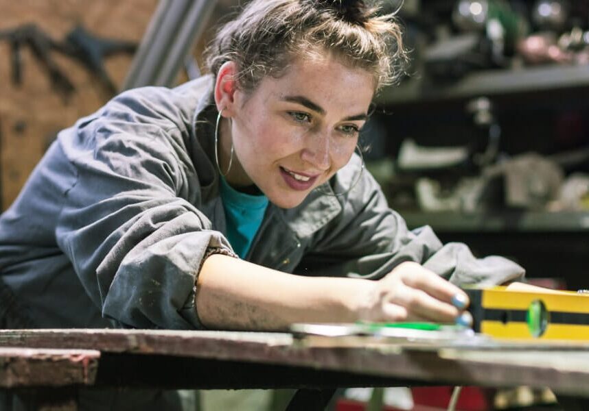 A female mechanic using a spirit level in a garage