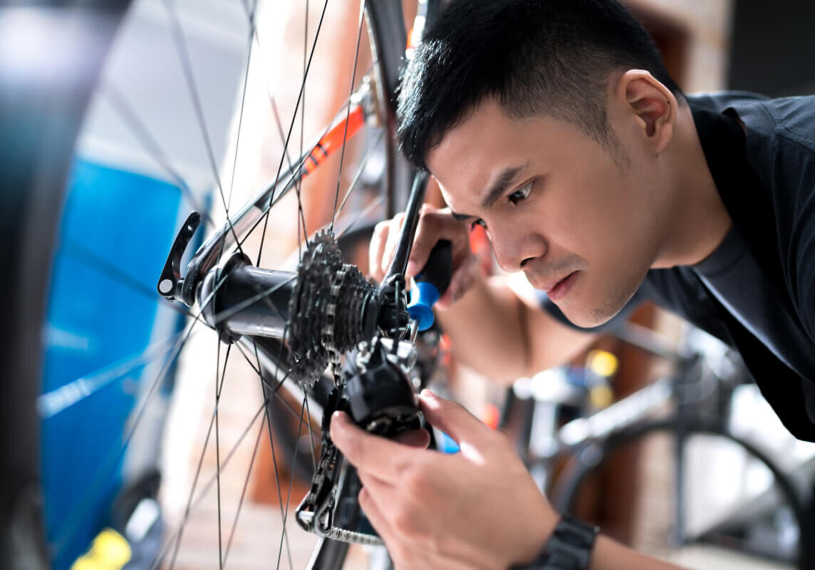 Young male bicycle mechanic fixing gears on a bike